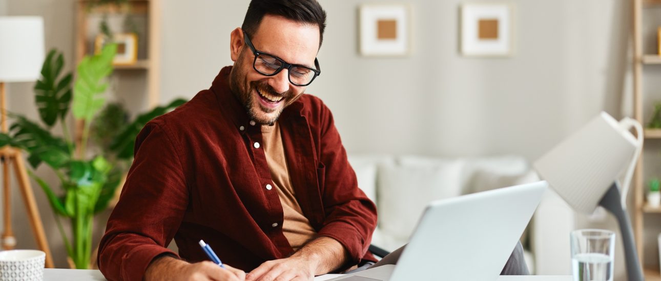 Young business man working at home with laptop and papers on desk Young business man working at home with laptop and papers on desk